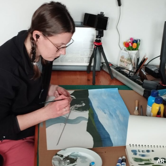 Annika sitting at her studio desk drawing and listening to music